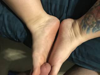 wife lying back on bed, her feet are playing with my cock